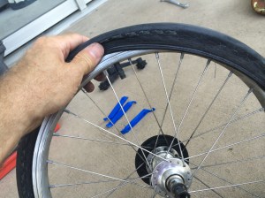 Easing the tire back onto the rim with my fingers only -- this is to avoid piercing it again with a tool.