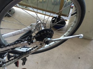 Using a wrench to put the wheel back on. The tension device comes after this.